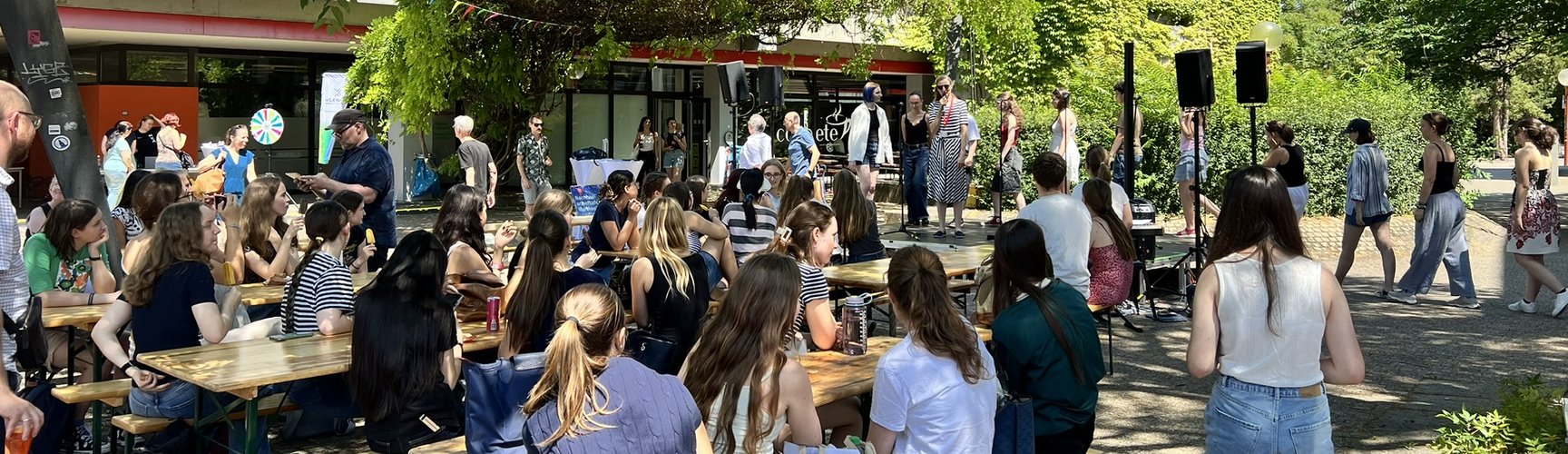 Studierende sitzen auf Bierbänken auf dem geschmückten Campus