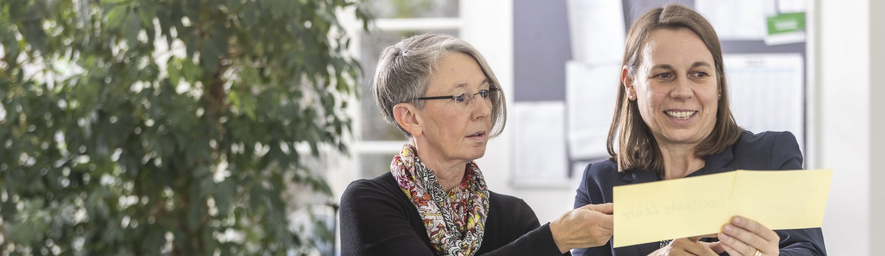 Zwei Frauen diskutieren an einem Stehtisch über die Inhalte von Karteikarten