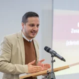 Ibrahim Aslandur spricht auf dem Podium ins Mikrophon