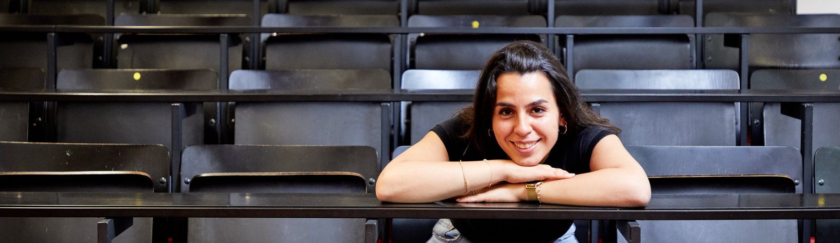 Eine Studentin sitzt alleine in einem Hörsaal