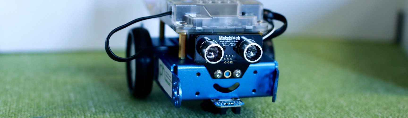 ein kleiner fahrbarer Roboter steht auf einem Teppich im LLL Informatik