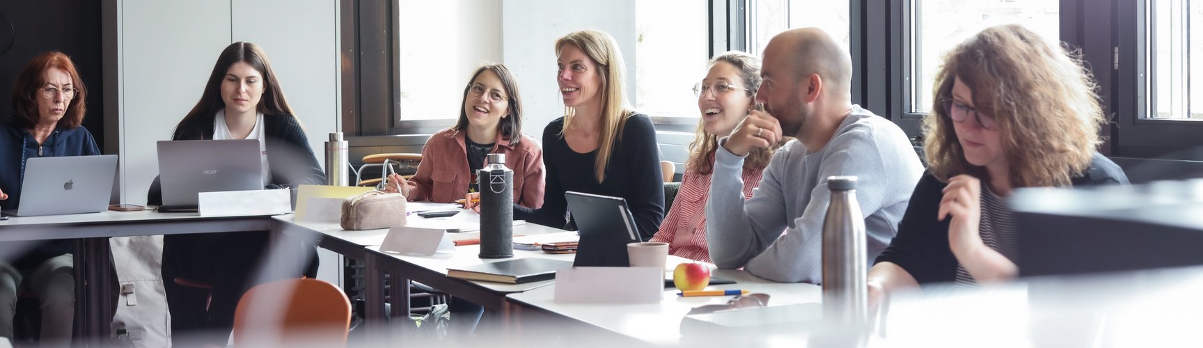 Mehrere Studierende sitzen in einem Hörsaal an ihren Computern und folgen dem Unterricht