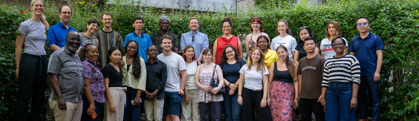 Gruppenfoto von Studierenden und Lehrenden, die in die Kamera lächeln