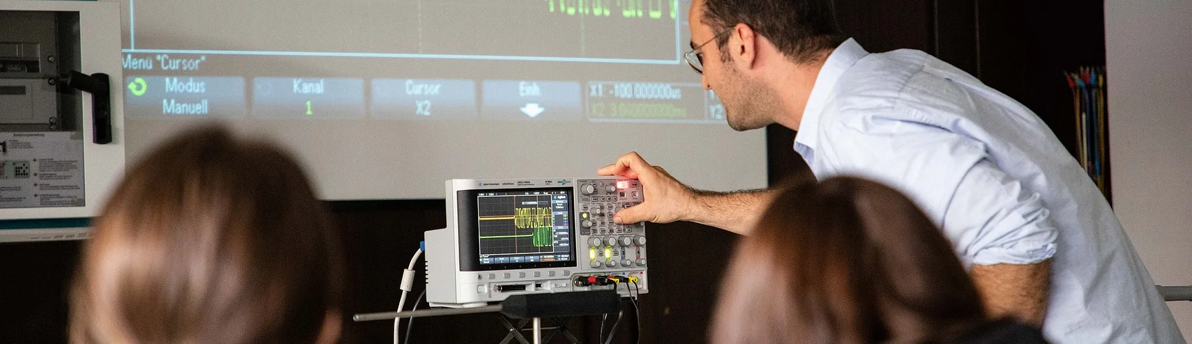 ein Lehrender arbeitet mit einer Gerätschaft vor Studierenden im Physikseminar