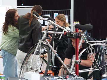 Drei junge Menschen reparieren Fahrräder