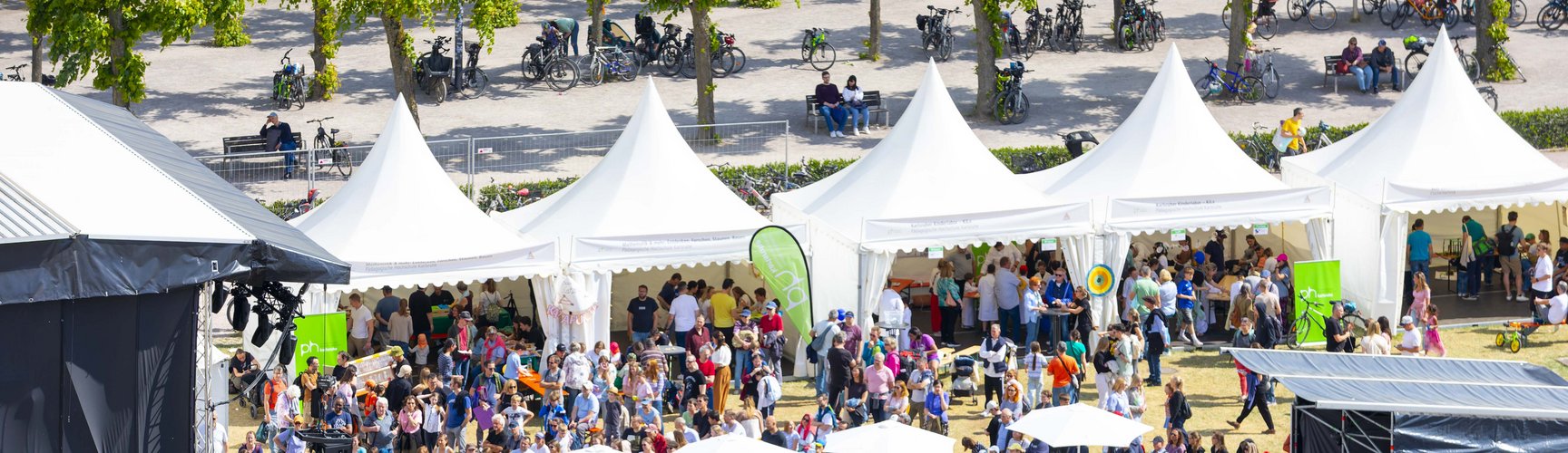 Ein Blick von oben auf das EFFEKTE Wissenschaftsfestival 2025. Zu sehen sind die von der PHKA bespielten Pagodenzelte, ein teil von der bühne und sehr viele Menschen. 