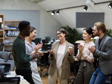 5 Personen stehen in einem Büro beisammen und sprechen miteinander.