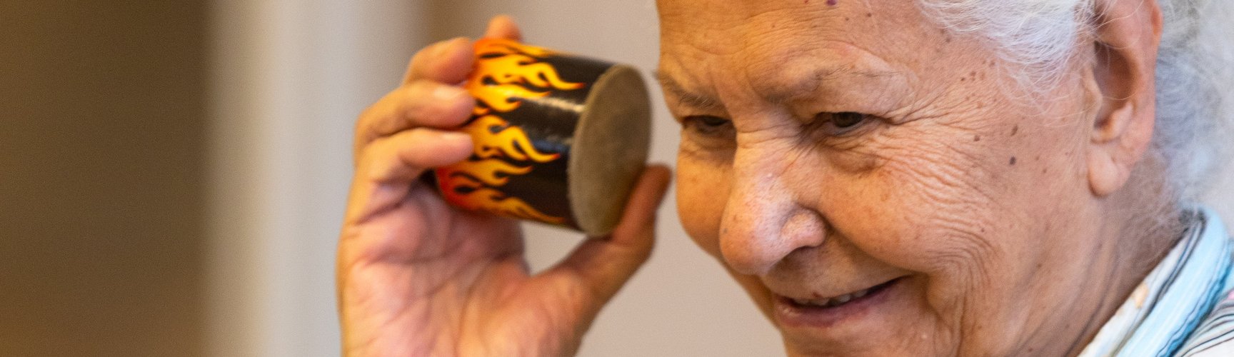 Seniorin hält eine kleine Trommel ans Ohr