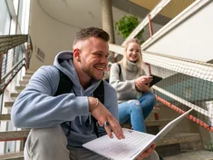 Zwei Studierende sitzen auf einer Treppe
