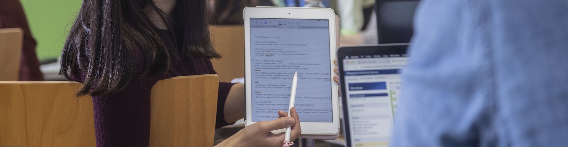 eine Studentin zeigt einem Kommilitonen Inhalte auf einem Tablet