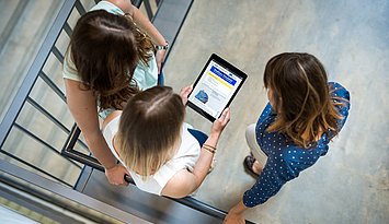Drei Studentinnen mit einem Tablet aus der Vogelperspektive