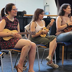 Drei Masterstudentinnen spielen Ukulele