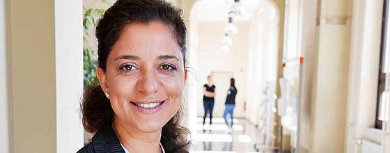 Eine Person blickt in die Kamera. Sie trägt Mappen im Arm.