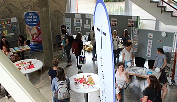 BIld praxisbörse Kindheitspädagogik Blick von oben auf verschiedene Stände und Besucher:innen bei der Praxisbörse der Praxisstelle Kindheitspädagogik