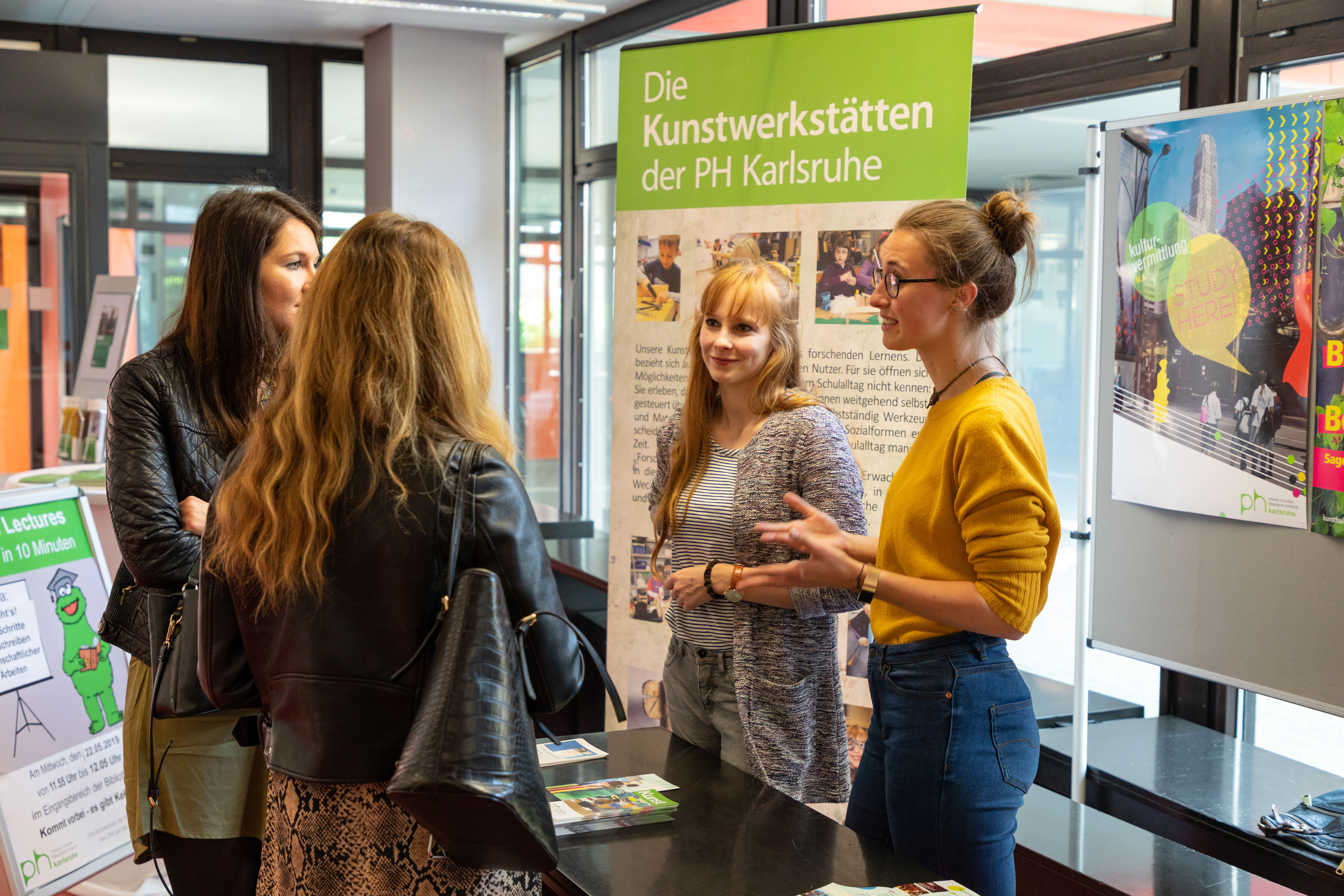 Zwei Studierende präsentieren an einem Infostand ihr Studienfach.